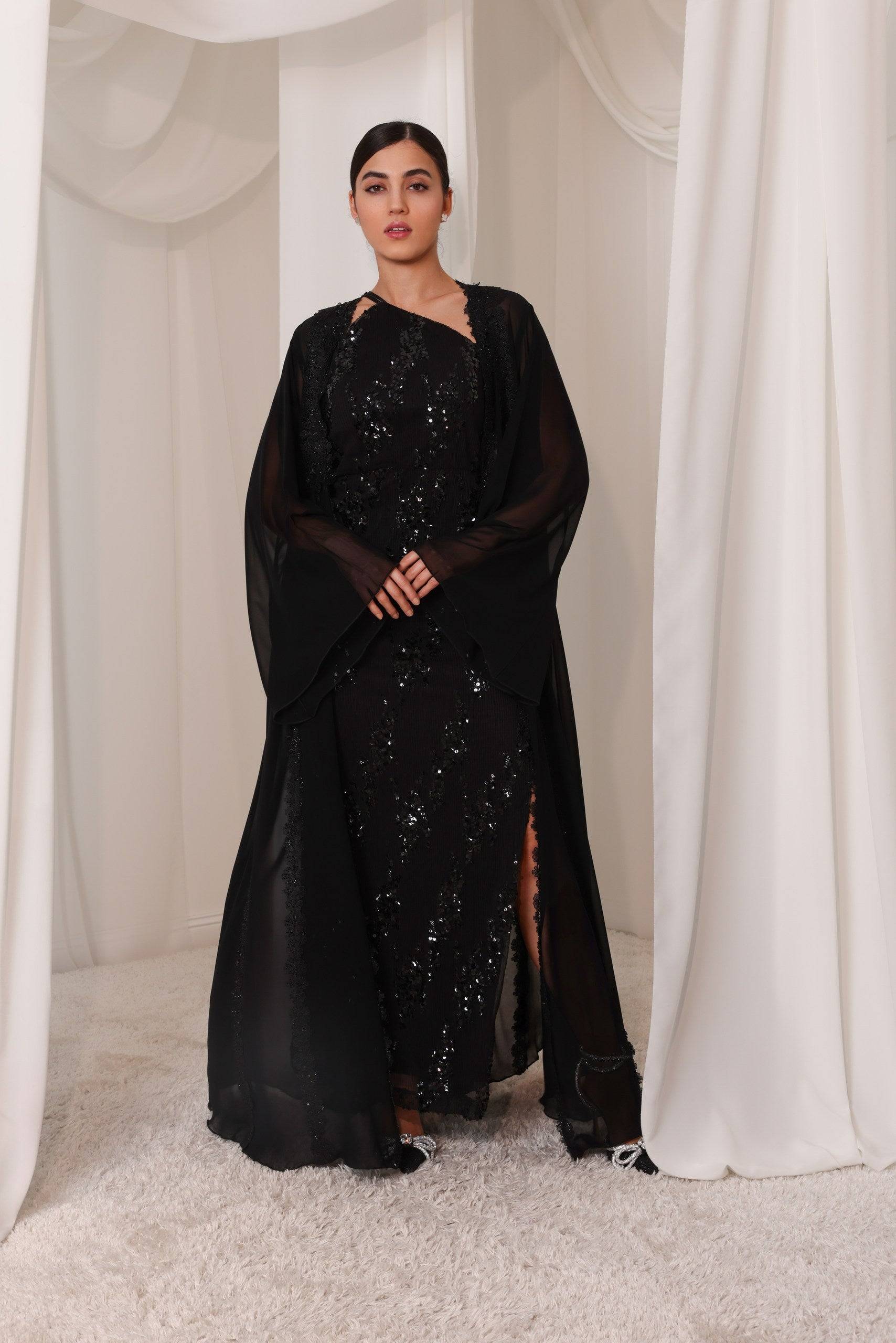 Sahara Shimmer black embroidered abaya with sheer fabric and floral detailing, styled elegantly for versatile wear in evening or day settings.