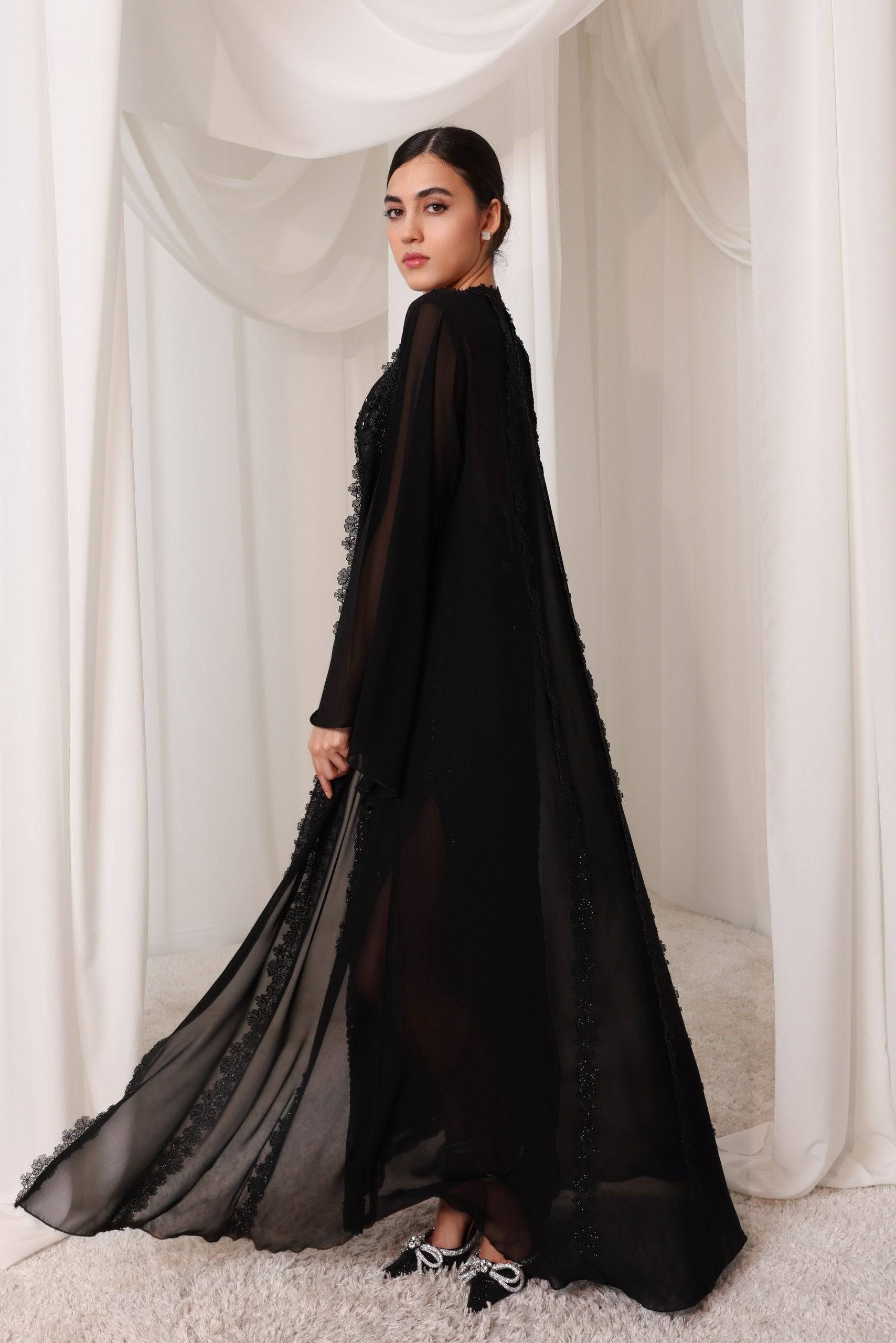 Sheer black Sahara Shimmer abaya with intricate embroidery, flowing silhouette, and delicate floral accents, perfect for sophisticated styling.